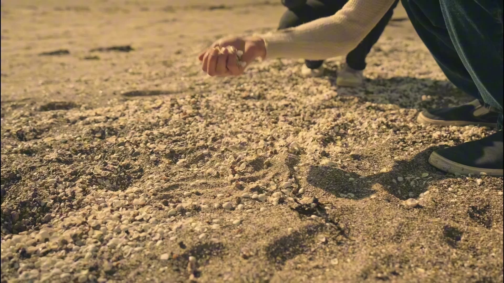 En hånd som slipper sand på en strand i lavt kveldslys, fra reklamefilmen for Autosentrum.