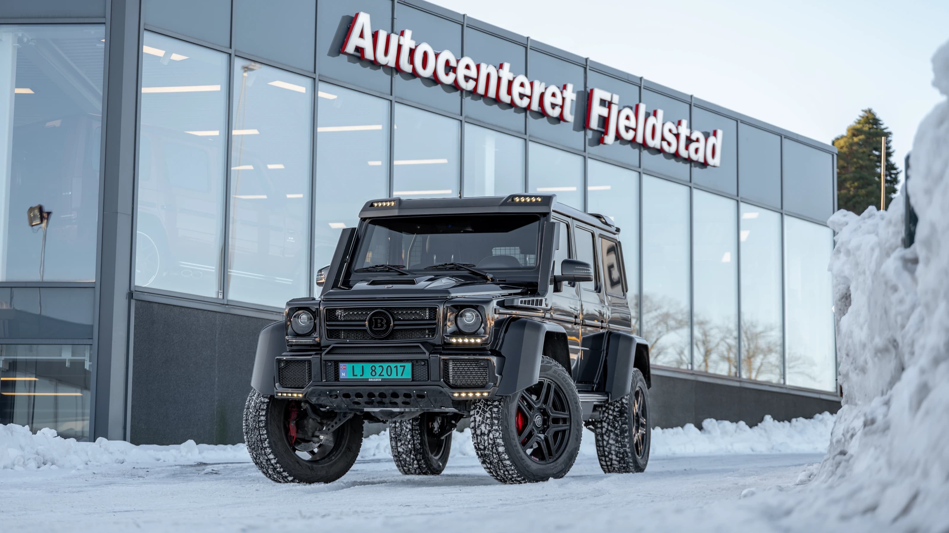 Svart G-Klasse parkert i snøen utenfor Autocenteret Fjeldstad i Holmestrand.