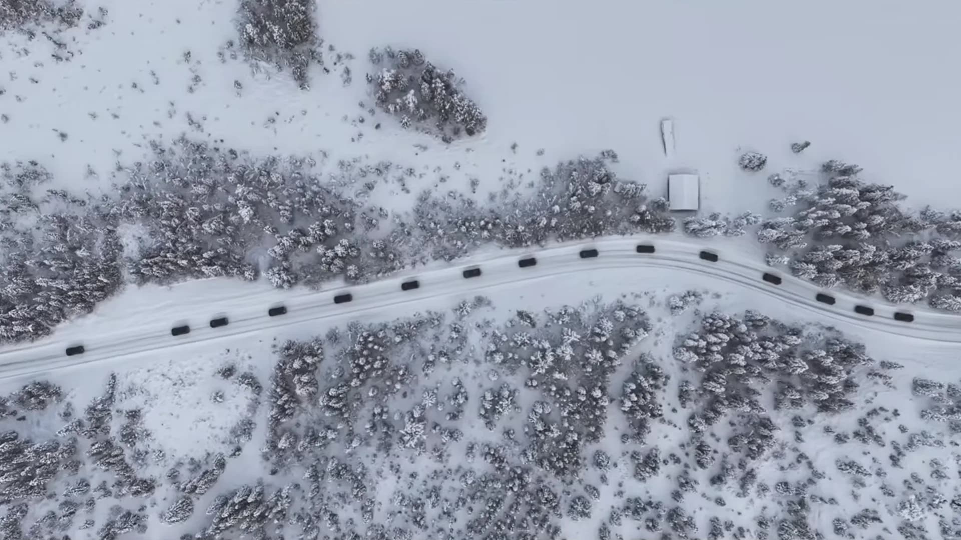 Dronebilde rett ovenfra av en kolonne biler på en snødekt fjellvei, fra kundetreffet på Storefjell.