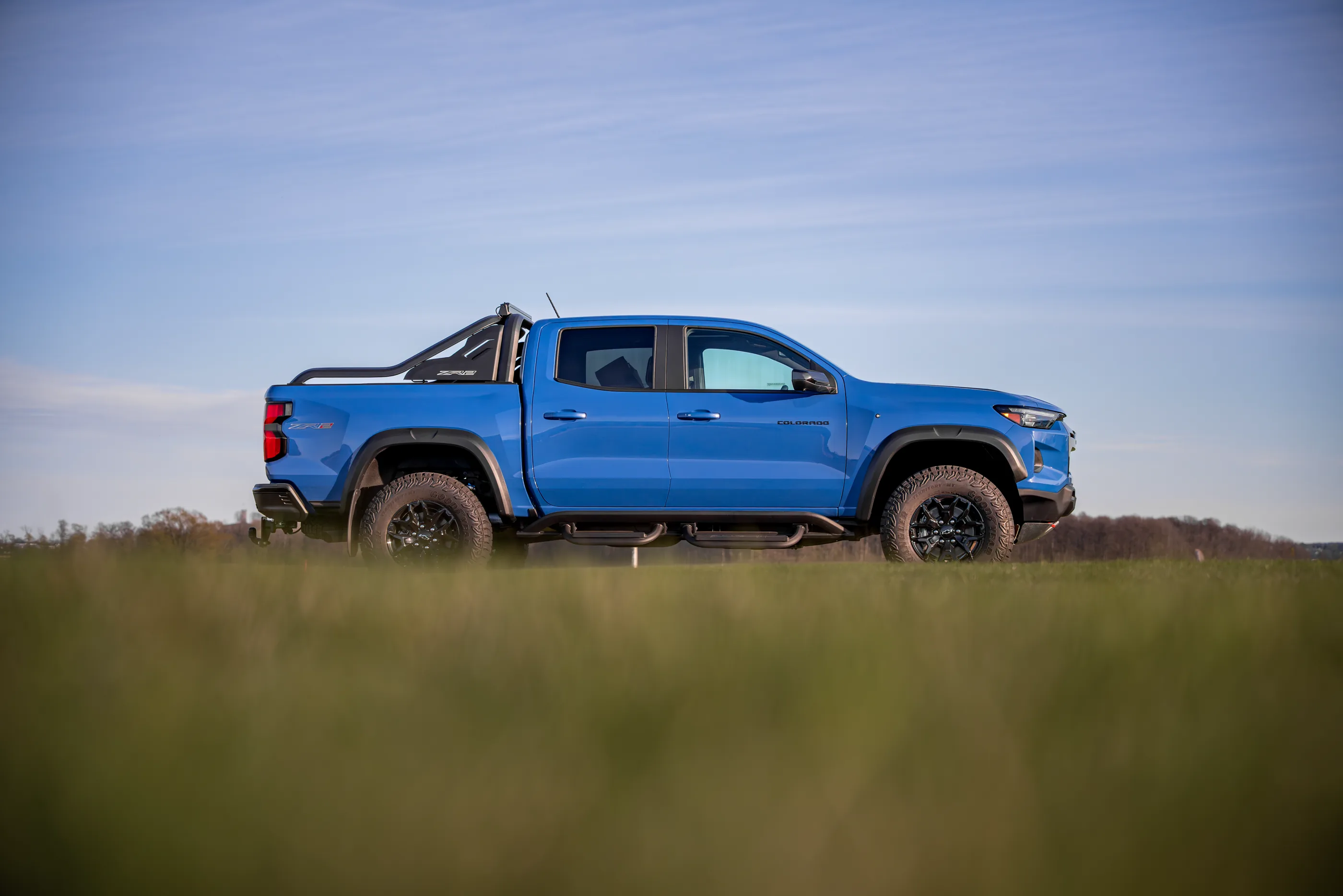En blå Chevrolet Colorado ZR2 sett fra siden, på et jorde mot blå himmel.