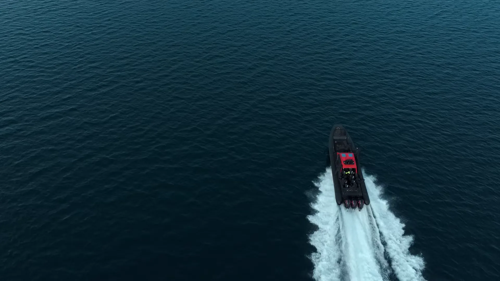 Dronebilde rett ovenfra av en RIB i full fart over mørkt fjordvann, fra musikkvideoen «Tribe» for Sarettii.