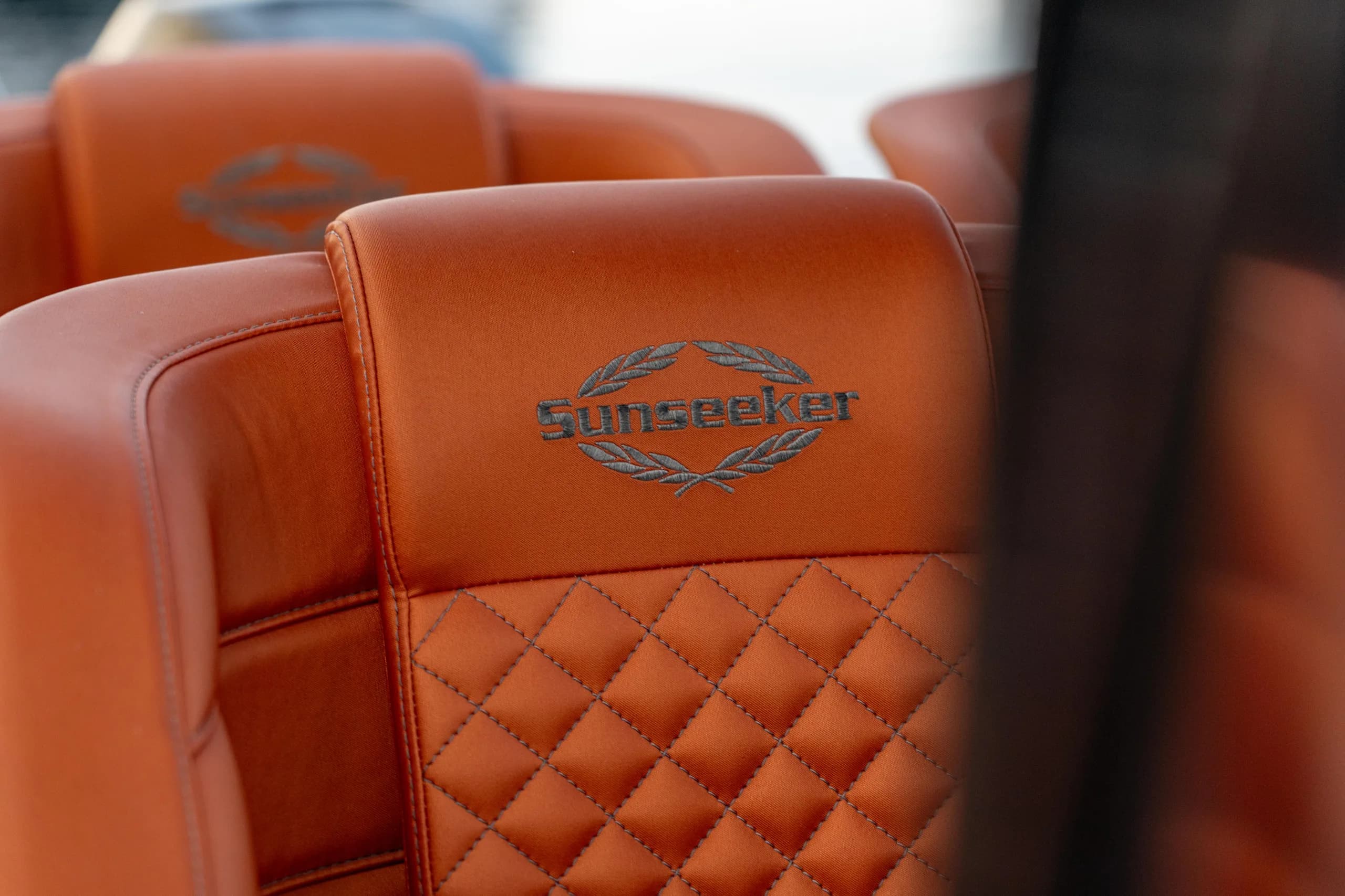 Nærbilde av quiltet Sunseeker-merket skinnstol i cognacfarge.