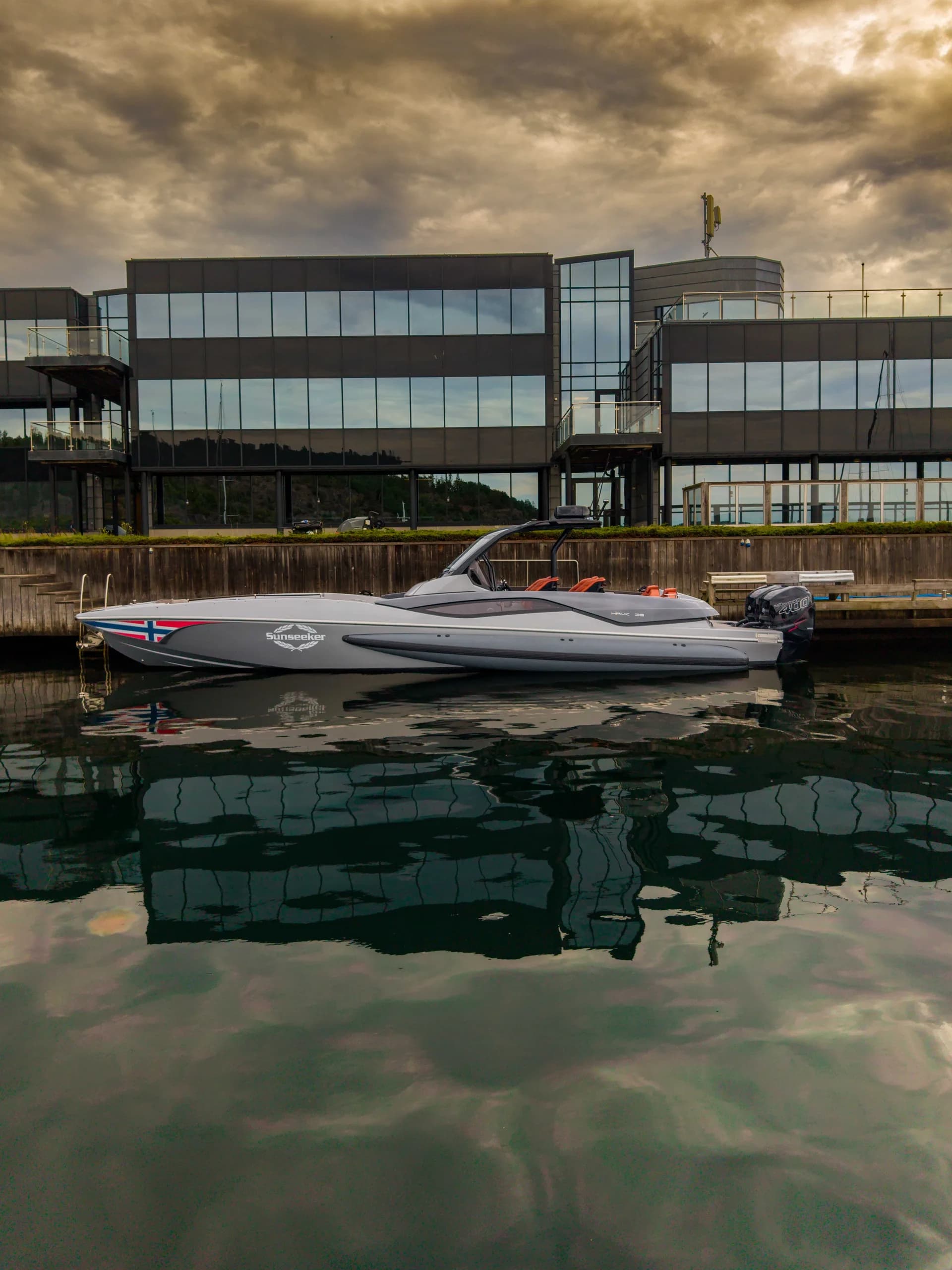 Sunseeker Hawk 38 fortøyd foran kontorbygg med dramatisk himmel.