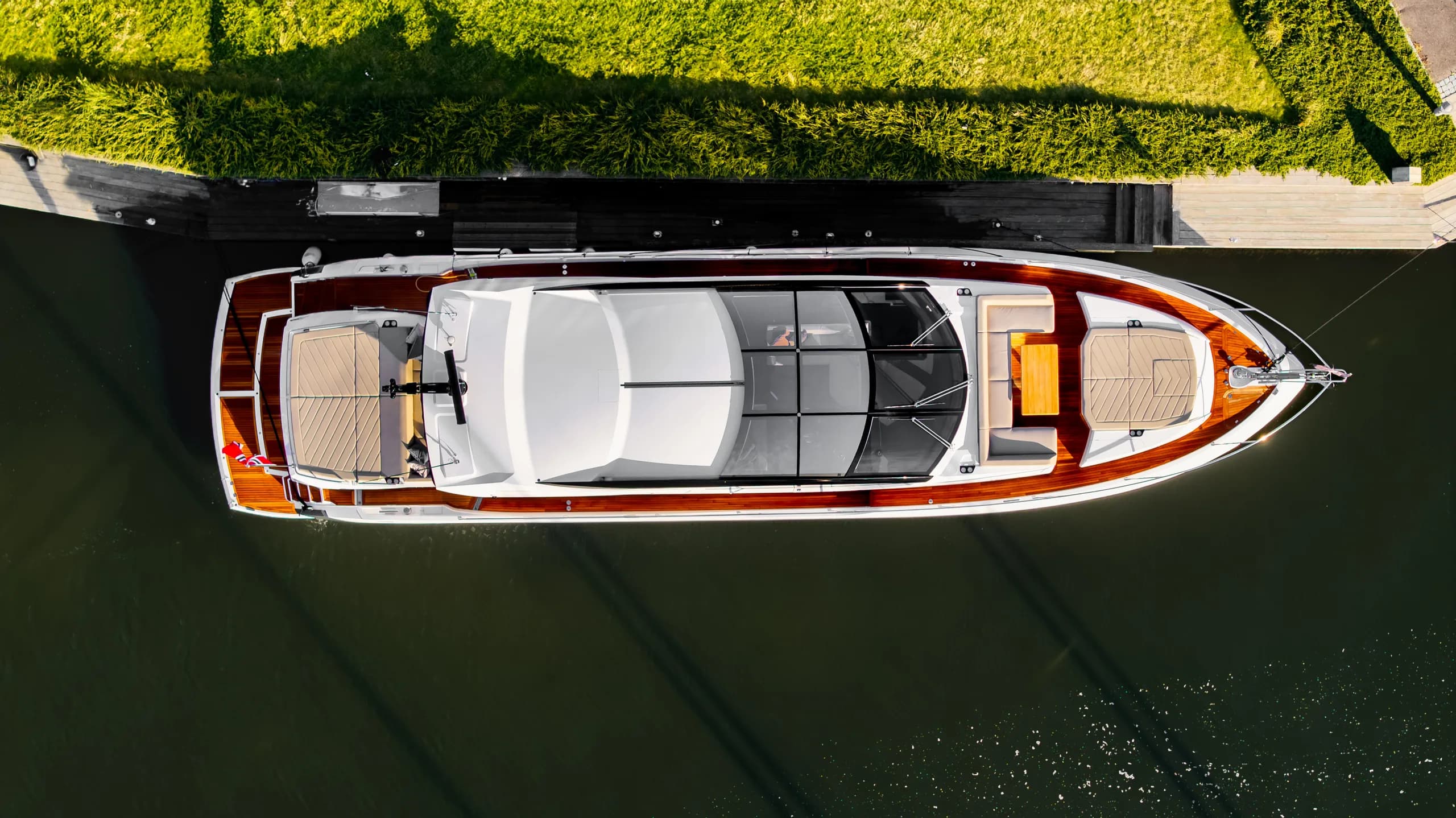 Fairline Targa 47 ovenfra ved brygga, dronebilde med teakdekk synlig.