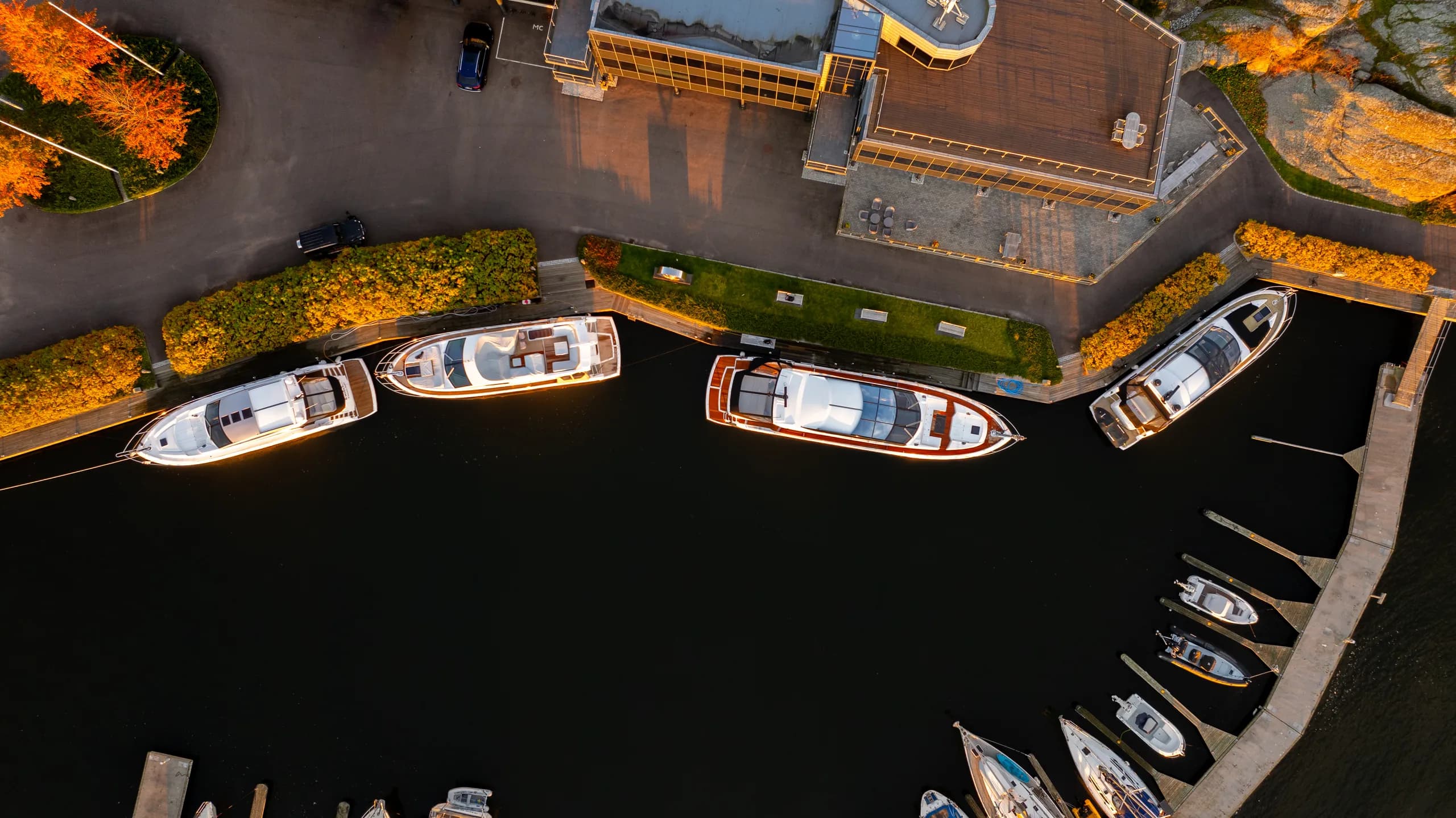 Sundal Yacht-marinaen i kveldslys sett fra drone, med tre yachter ved brygga.