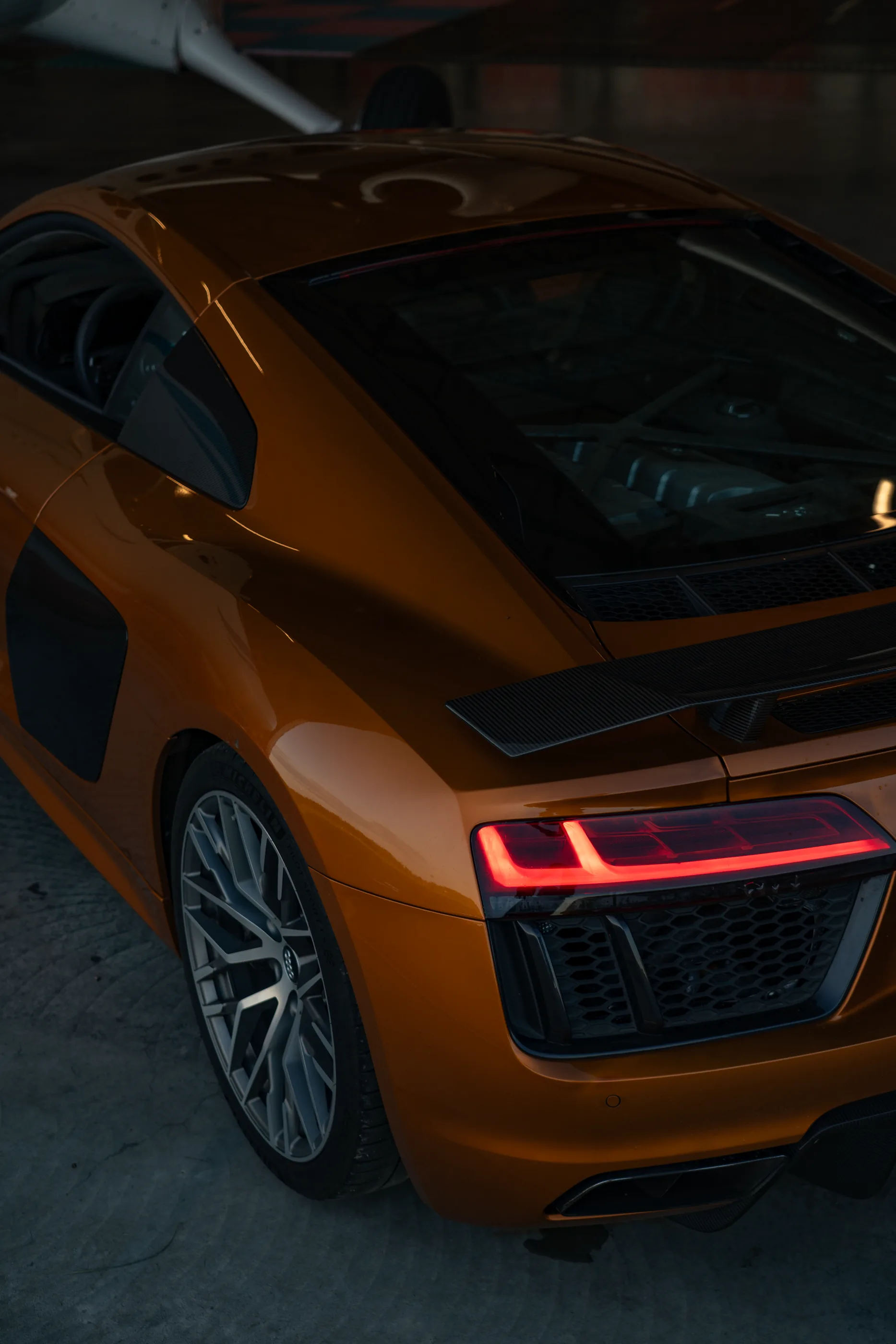 Oransje Audi R8 sett bakfra i en mørk hangar.